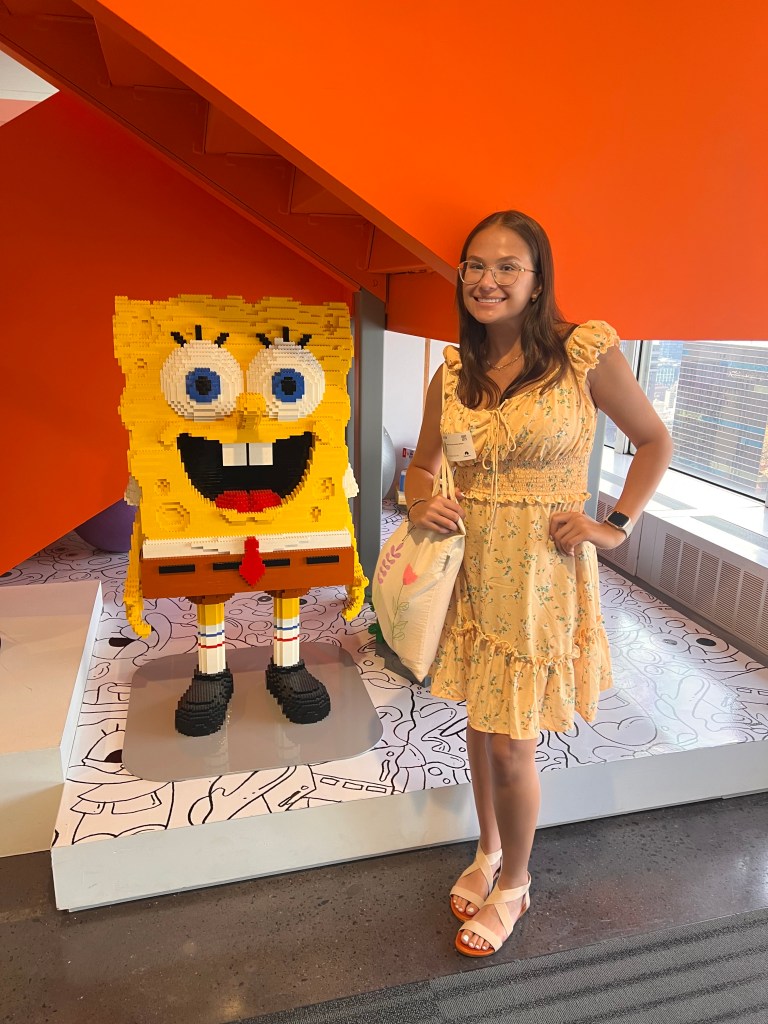 Daniela Galvez-Cepeda is standing smiling next to a Lego figure of Sponge Bob